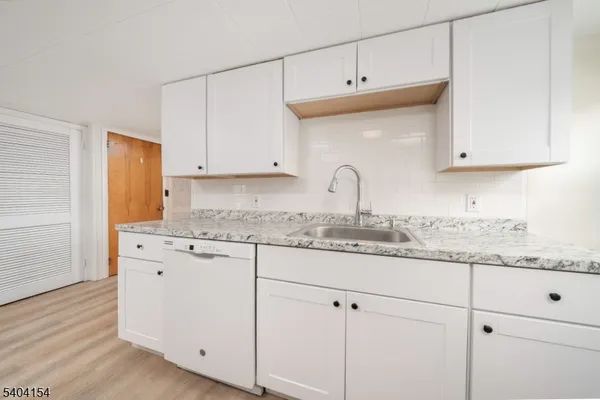 a kitchen with granite countertop white cabinets and a sink