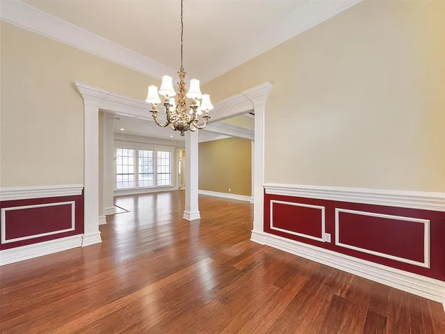 a view of a livingroom with wooden floor a chandelier and windows