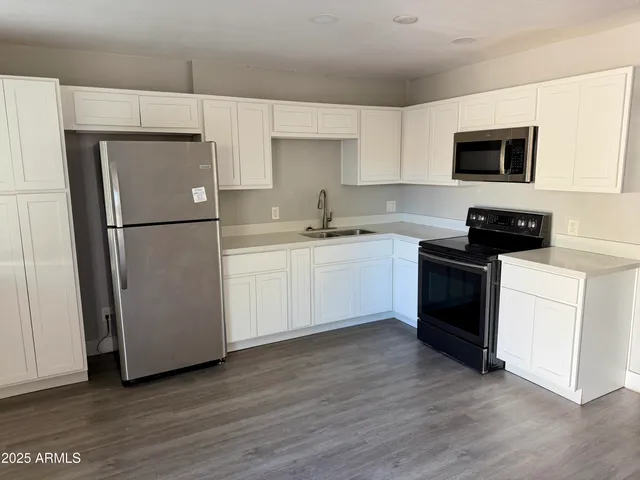 a kitchen with a sink a refrigerator a microwave and cabinets