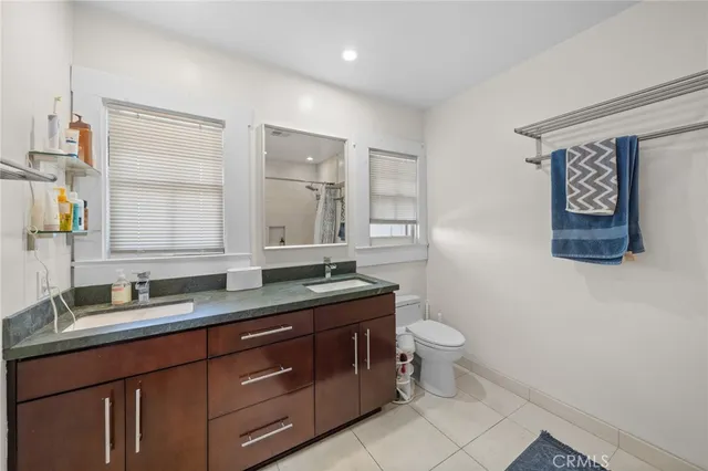 a bathroom with a granite countertop sink a toilet and a mirror