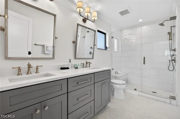 a bathroom with a double vanity sink toilet and shower