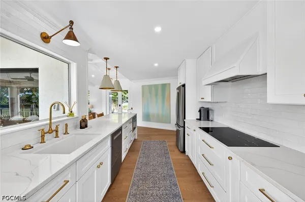 a large white kitchen with a lot of counter space and wooden floor