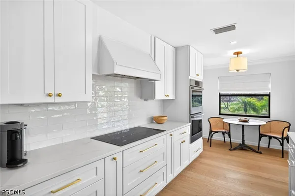 a kitchen with stainless steel appliances a sink a stove and white cabinets