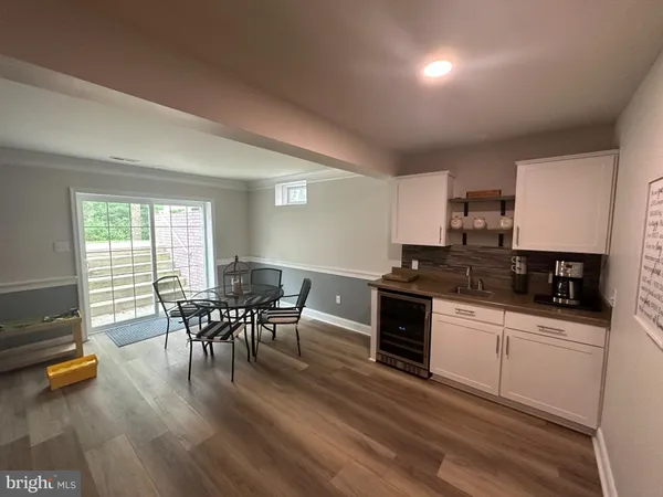 a kitchen with stainless steel appliances granite countertop a stove a sink a dining table and chairs with wooden floor