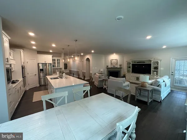 a large living room with stainless steel appliances kitchen island granite countertop a refrigerator and a dining table