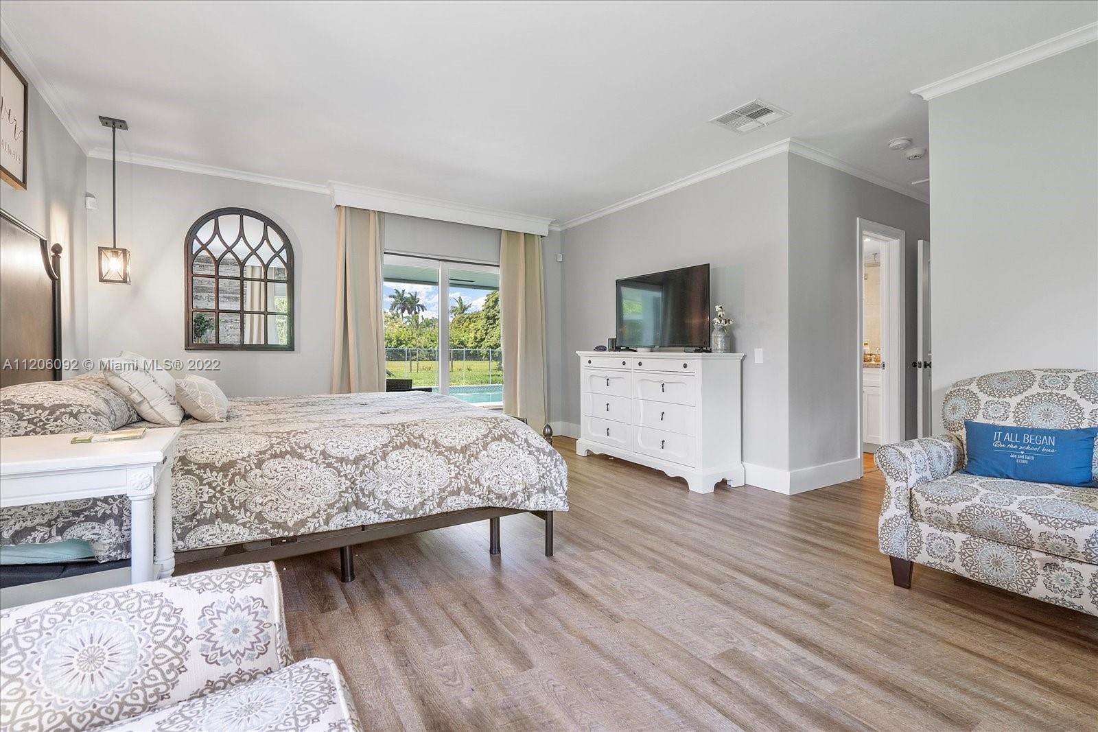 17300 Southwest 294th Street Homestead, FL 33030 - Photo 30 of 50 a spacious bedroom with a large bed a chandelier and windows