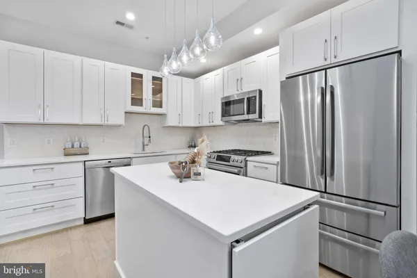 a kitchen with kitchen island a white cabinets and refrigerator