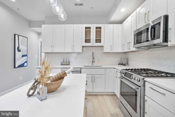 a kitchen with stainless steel appliances granite countertop a stove and white cabinets