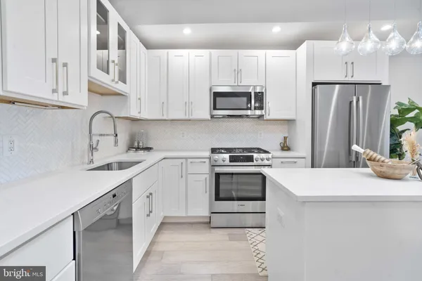 a kitchen with stainless steel appliances granite countertop a sink stove a refrigerator and white cabinets with wooden floor