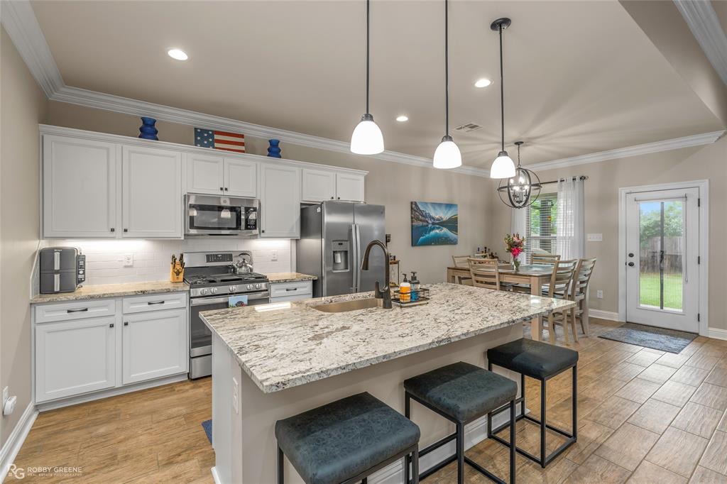 122 Brimestone Loop Benton, LA 71006 - Photo 5 of 33 a kitchen with granite countertop a stove a sink a dining table and chairs with wooden floor