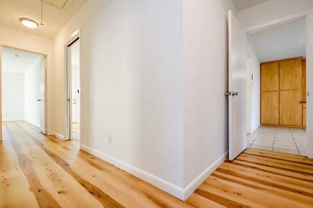 a view of a hallway with wooden floor and bathroom