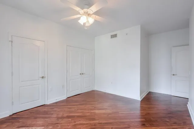 an empty room with wooden floor closet and windows