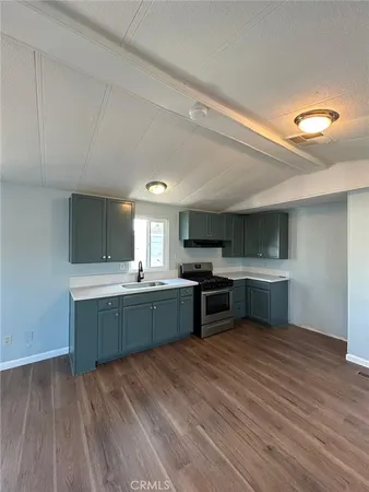 a kitchen with stainless steel appliances kitchen island granite countertop a sink cabinets and wooden floor