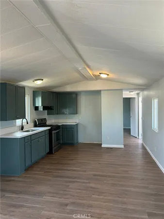 a large white kitchen with a sink and dishwasher a stove top oven with wooden floor