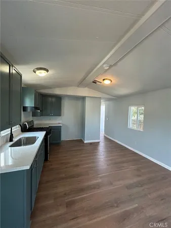 a large white kitchen with a sink and dishwasher a stove with wooden floor