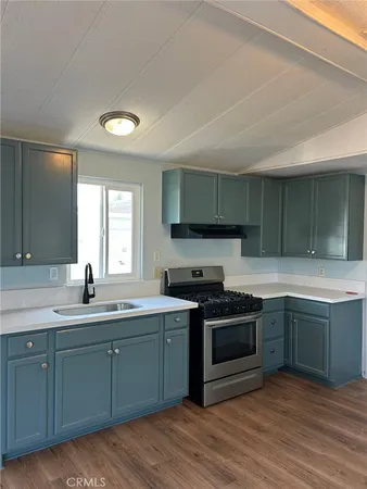 a kitchen with stainless steel appliances granite countertop a sink and cabinets with wooden floor