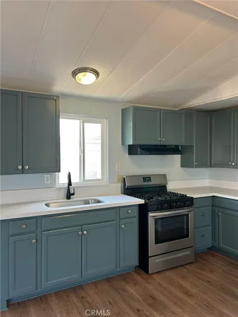 a kitchen with stainless steel appliances granite countertop a sink a stove a refrigerator cabinets and wooden floor