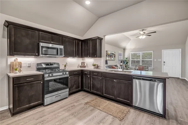 a kitchen with stainless steel appliances granite countertop wooden cabinets a stove top oven a sink and dishwasher