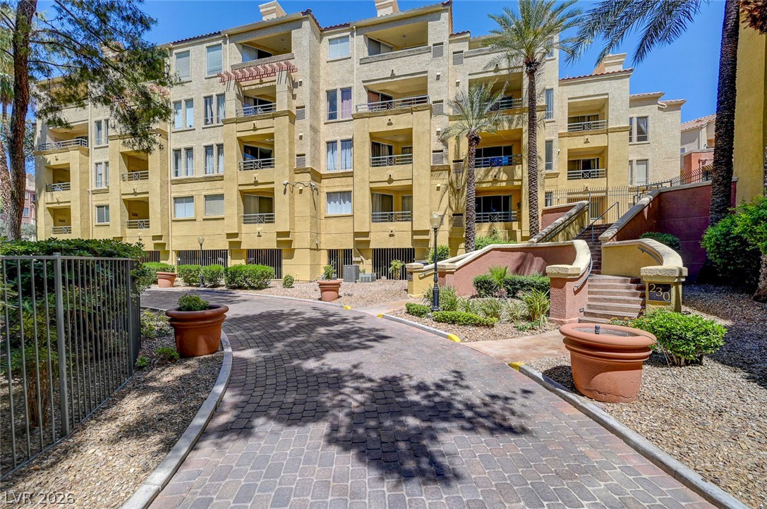 230 East Flamingo Road, Unit 106 Las Vegas, NV 89169 - Photo 30 of 66 A terracotta-toned building with private balconies overlooks a paver driveway, accented by lush landscaping.
