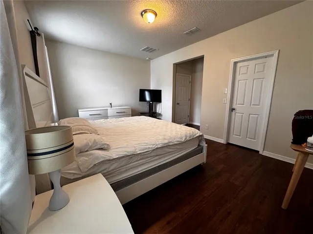 a view of an empty room with closet and wooden floor
