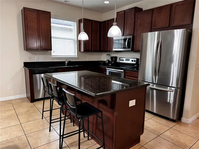 a kitchen with stainless steel appliances granite countertop a refrigerator a sink and a stove