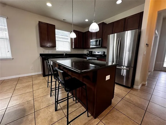 a kitchen with stainless steel appliances granite countertop a refrigerator a sink and a stove
