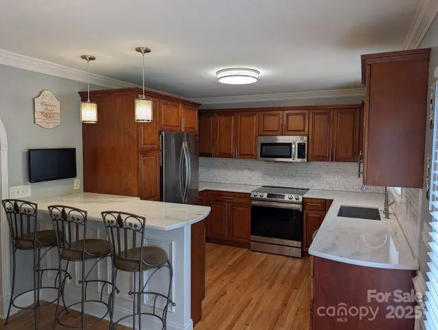 a kitchen with granite countertop a stove top oven a sink dishwasher a dining table and chairs with wooden floor