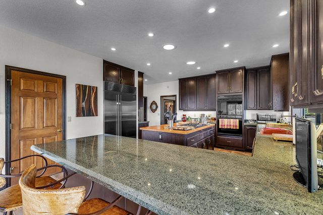 a large living room with stainless steel appliances kitchen island granite countertop a couch and wooden cabinets