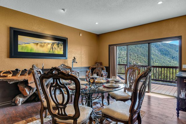 a view of a dining room with furniture one side kitchen view and wooden floor