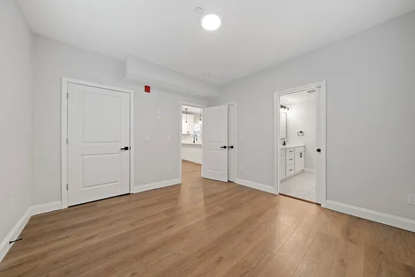 an empty room with wooden floor & windows and bathroom