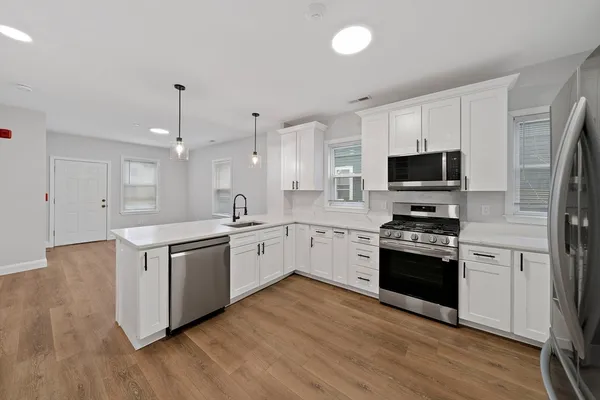 a large kitchen with cabinets wooden floor and stainless steel appliances
