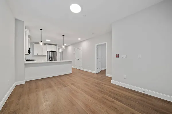 a view of kitchen and empty room with wooden floor