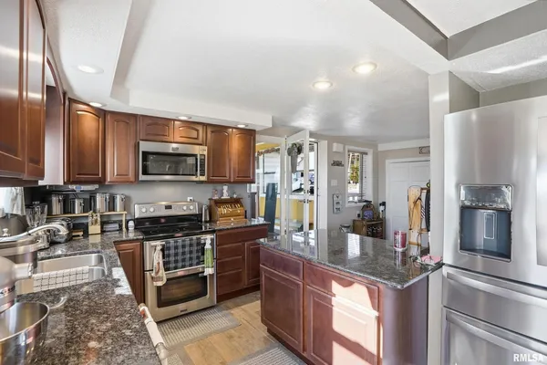 a kitchen with stainless steel appliances granite countertop a stove top oven a sink dishwasher and cabinets with wooden floor