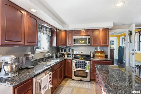 a kitchen with granite countertop a stove a sink dishwasher and cabinets with wooden floor