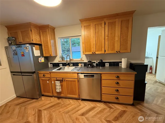 a kitchen with stainless steel appliances granite countertop a refrigerator a stove a sink and a white cabinets