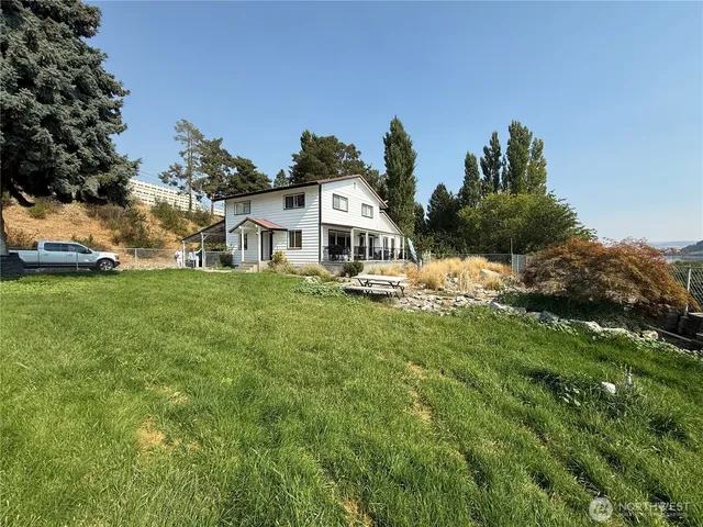 a view of a white house with a big yard and large trees