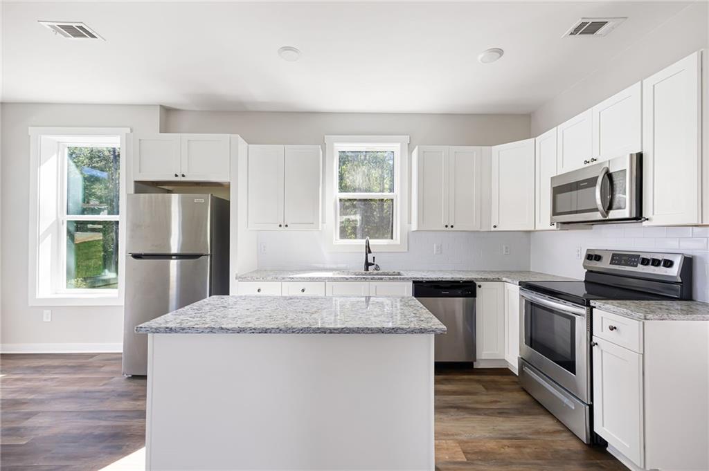 205 Pinecrest Road Cedartown, GA 30125 - Photo 13 of 27 a kitchen with stainless steel appliances granite countertop a stove a sink dishwasher a refrigerator and a microwave oven with wooden floor