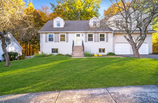 a front view of a house with a yard and trees