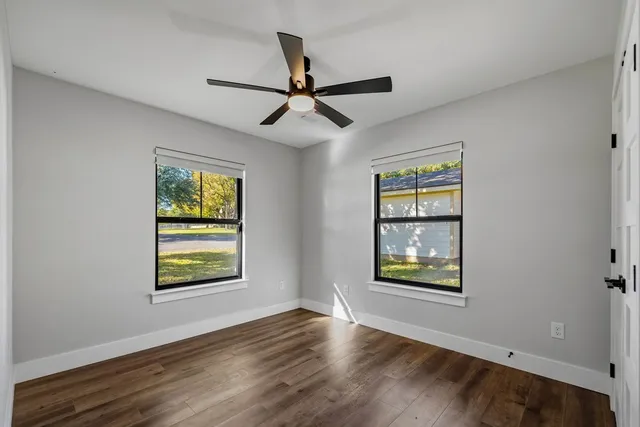 a view of an empty room with a window and wooden floor