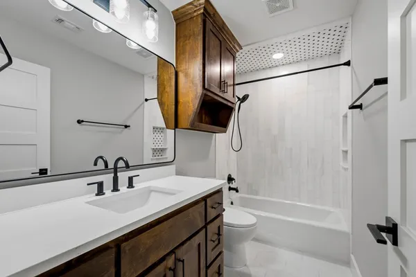 a bathroom with a sink a toilet a mirror and shower