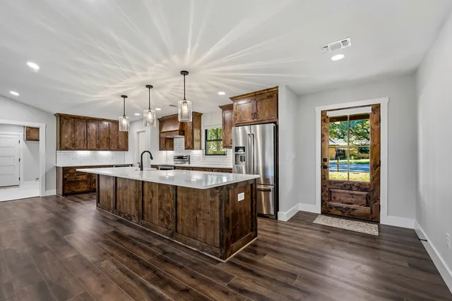 a large kitchen with stainless steel appliances granite countertop a lot of counter space and wooden floor