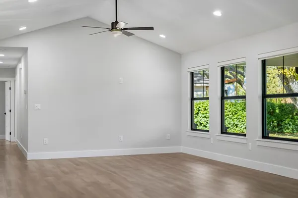 an empty room with windows and ceiling fan