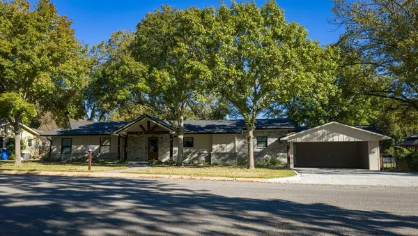 a front view of a house with a garden and trees