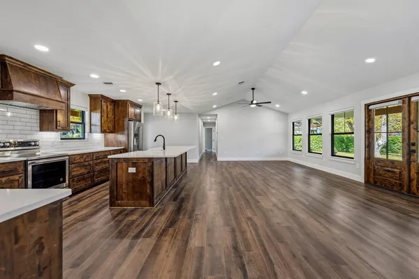 a large kitchen with stainless steel appliances granite countertop a large center island attached withe living room