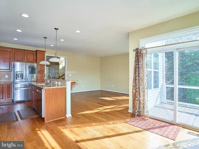 a room with kitchen island stainless steel appliances wooden floor and view living room
