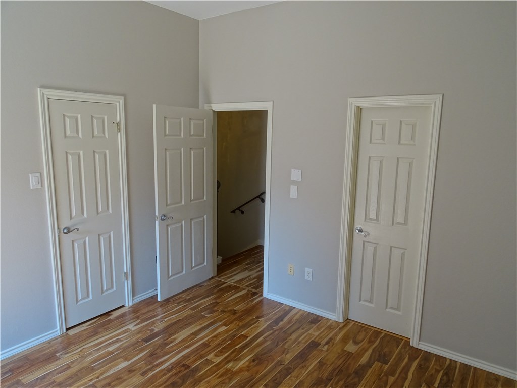 2918 Ranch Road 620, Unit K170 Austin, TX 78734 - Photo 12 of 22 Natural wood flooring complements clean walls, leading to an open doorway and multiple panel doors.