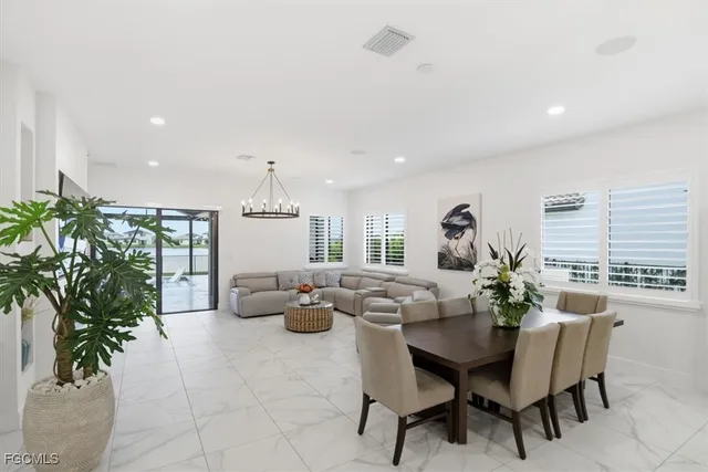 a kitchen with stainless steel appliances kitchen island granite countertop a refrigerator a stove a sink dishwasher and a dining table with wooden floor