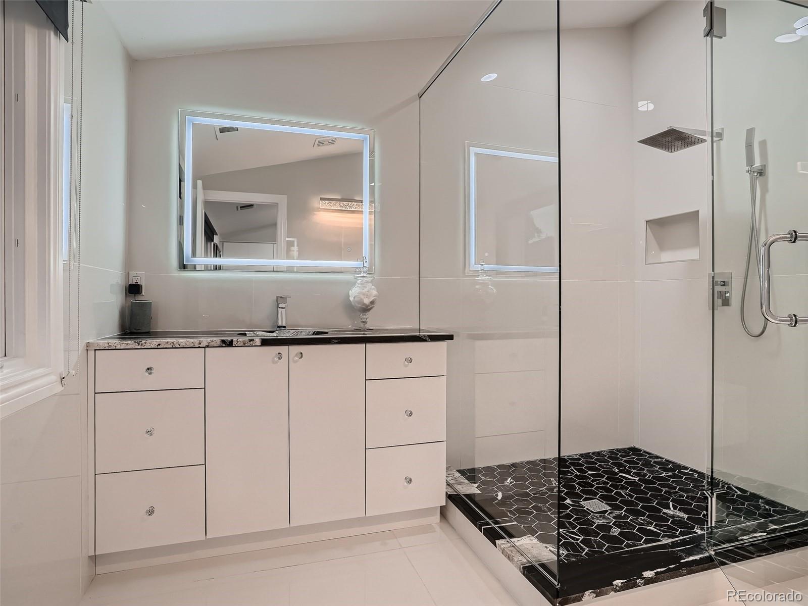 338 St Paul Street Denver, CO 80206 - Photo 31 of 40 a bathroom with a granite countertop sink a mirror and shower