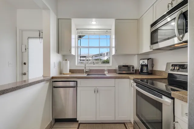 a kitchen with cabinets appliances a sink and a window