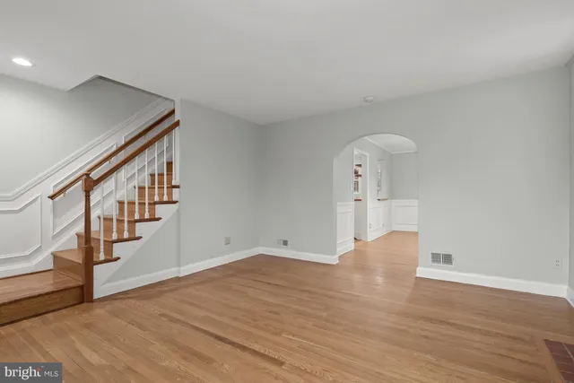 a view of an empty room with wooden floor and stairs